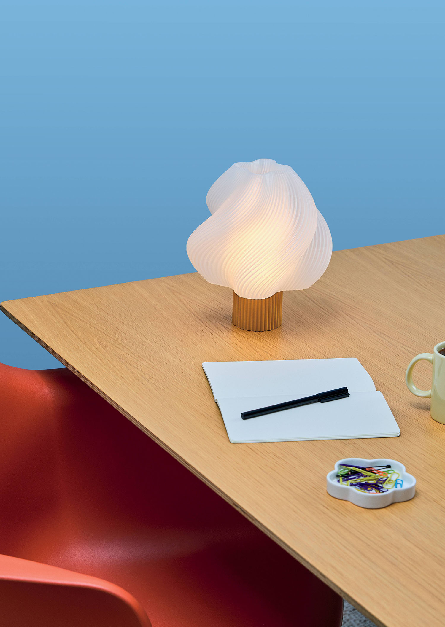 A table with a laptop, a cup and a lamp.