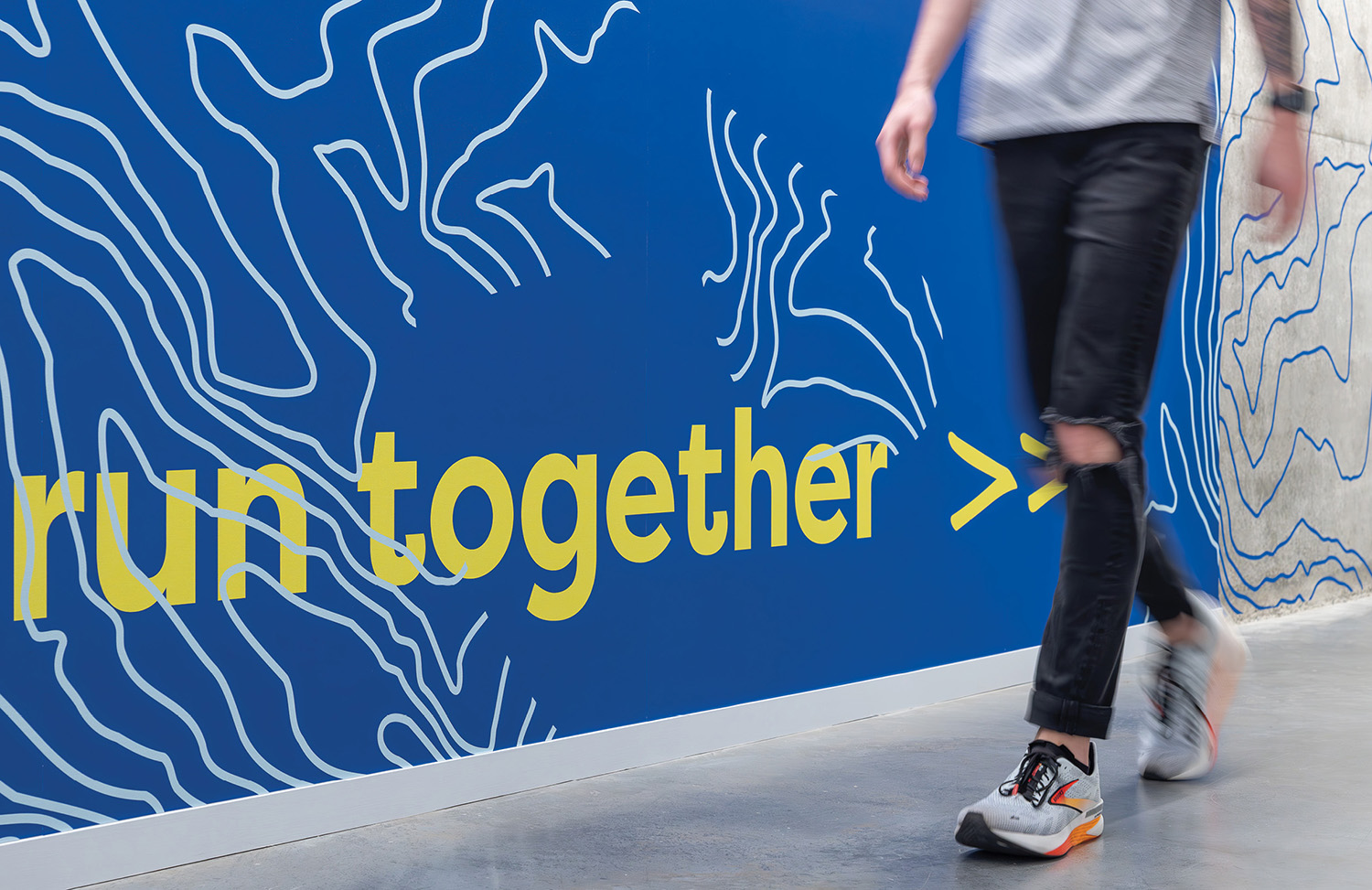 A man walking in front of a wall with a sign