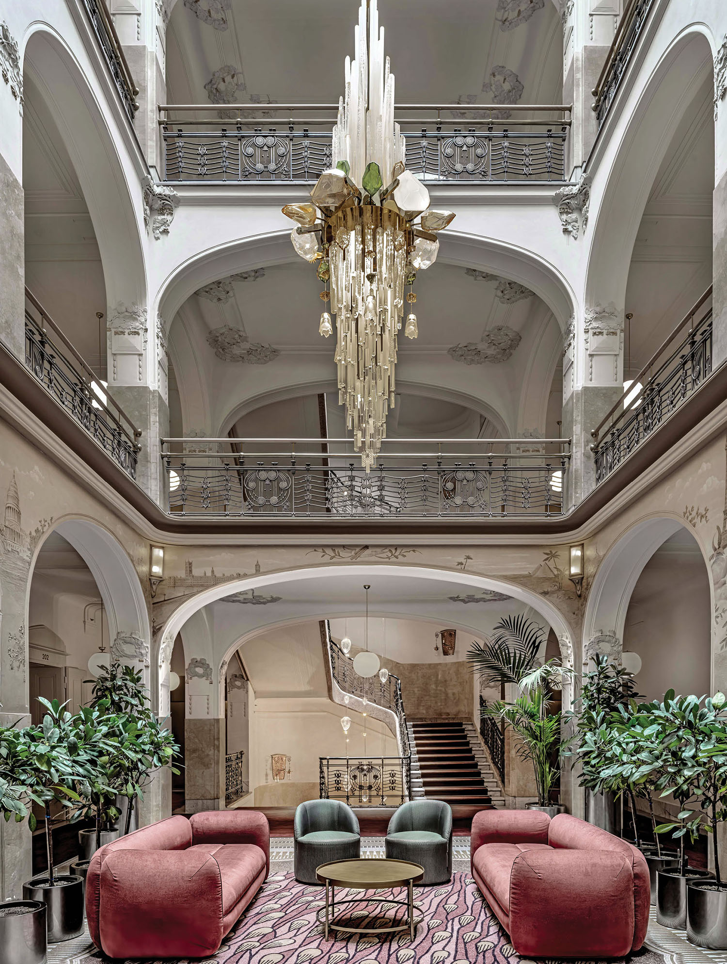 A large room with a large chandel and a pink couch.