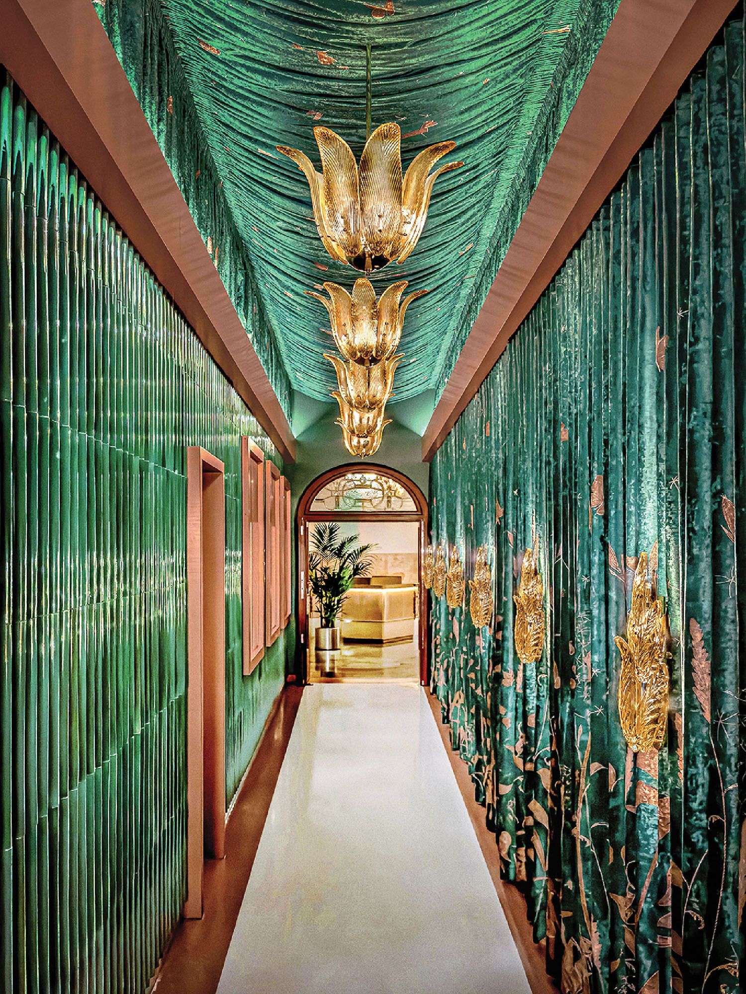 A long hallway with green curtains and a chandel.