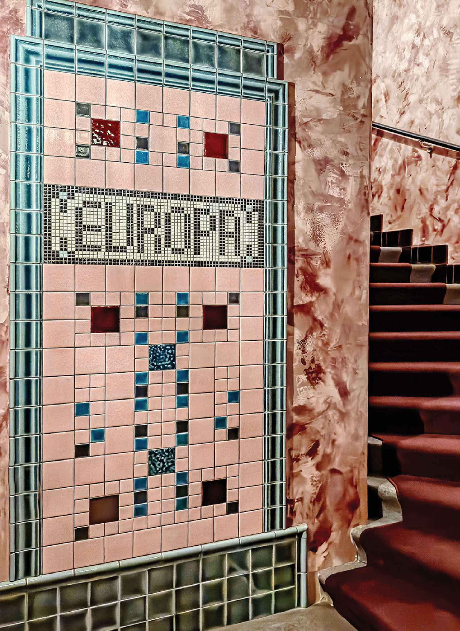 A tiled wall with a sign that says the name of a restaurant.