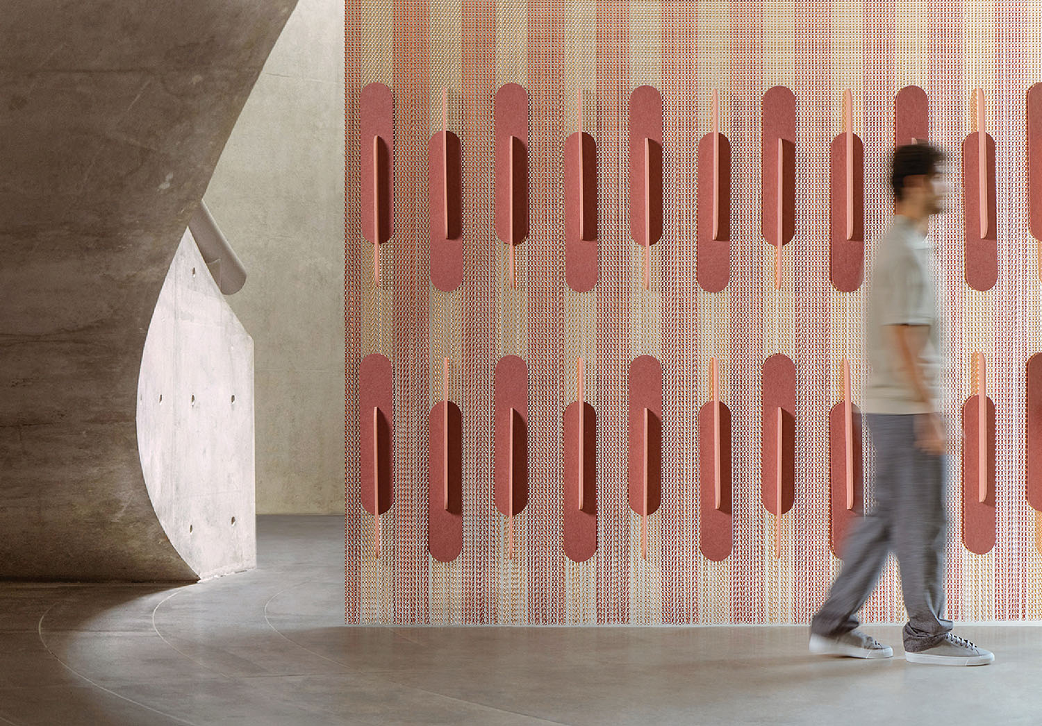 A man walking past a wall with a pattern on it.