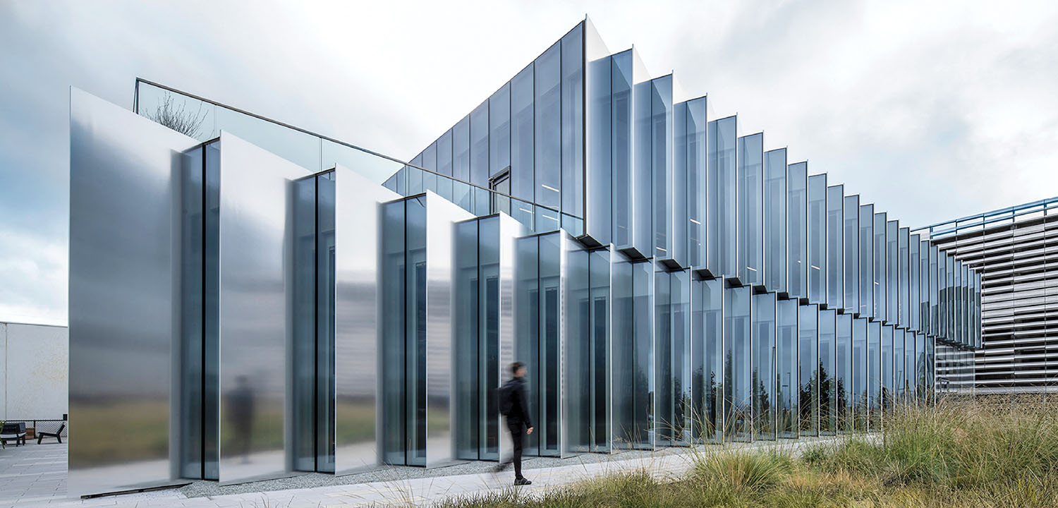 A man walking past a building with glass walls