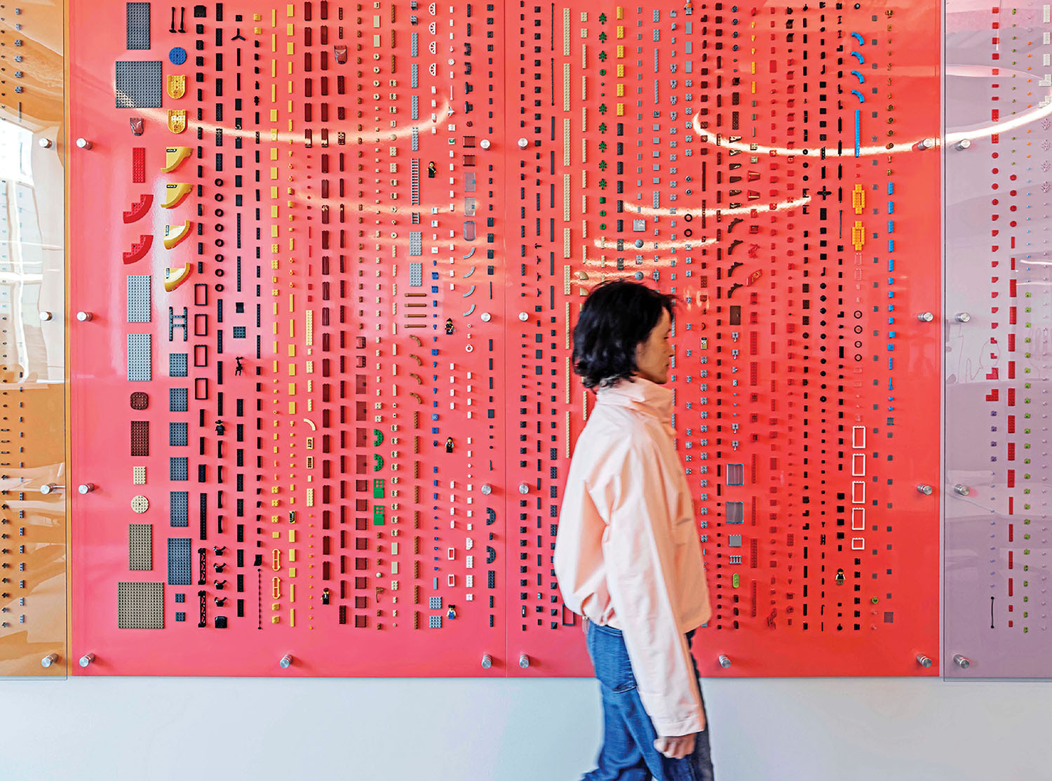 A woman standing in front of a pink wall with a large red piece.