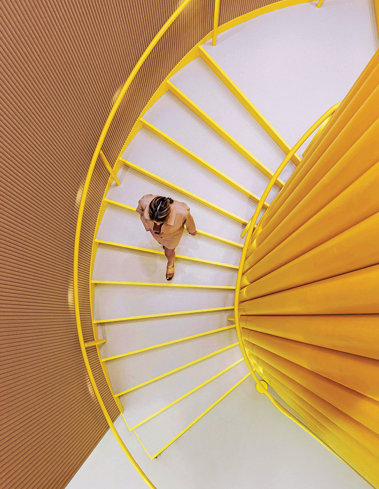 A woman is walking up a spiral staircase.