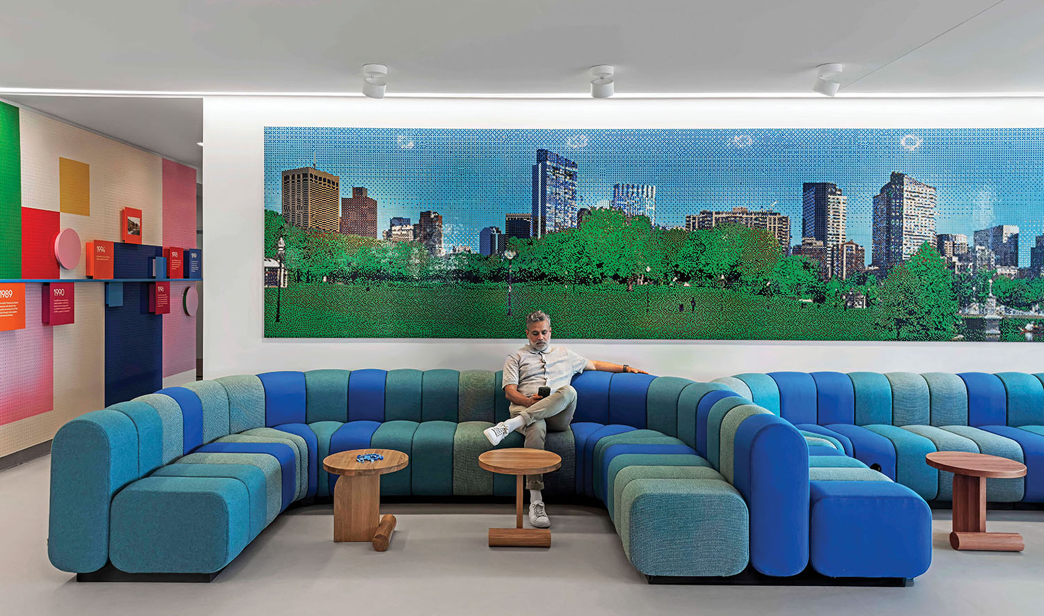 A man sitting in a blue couch in a room with colorful walls.