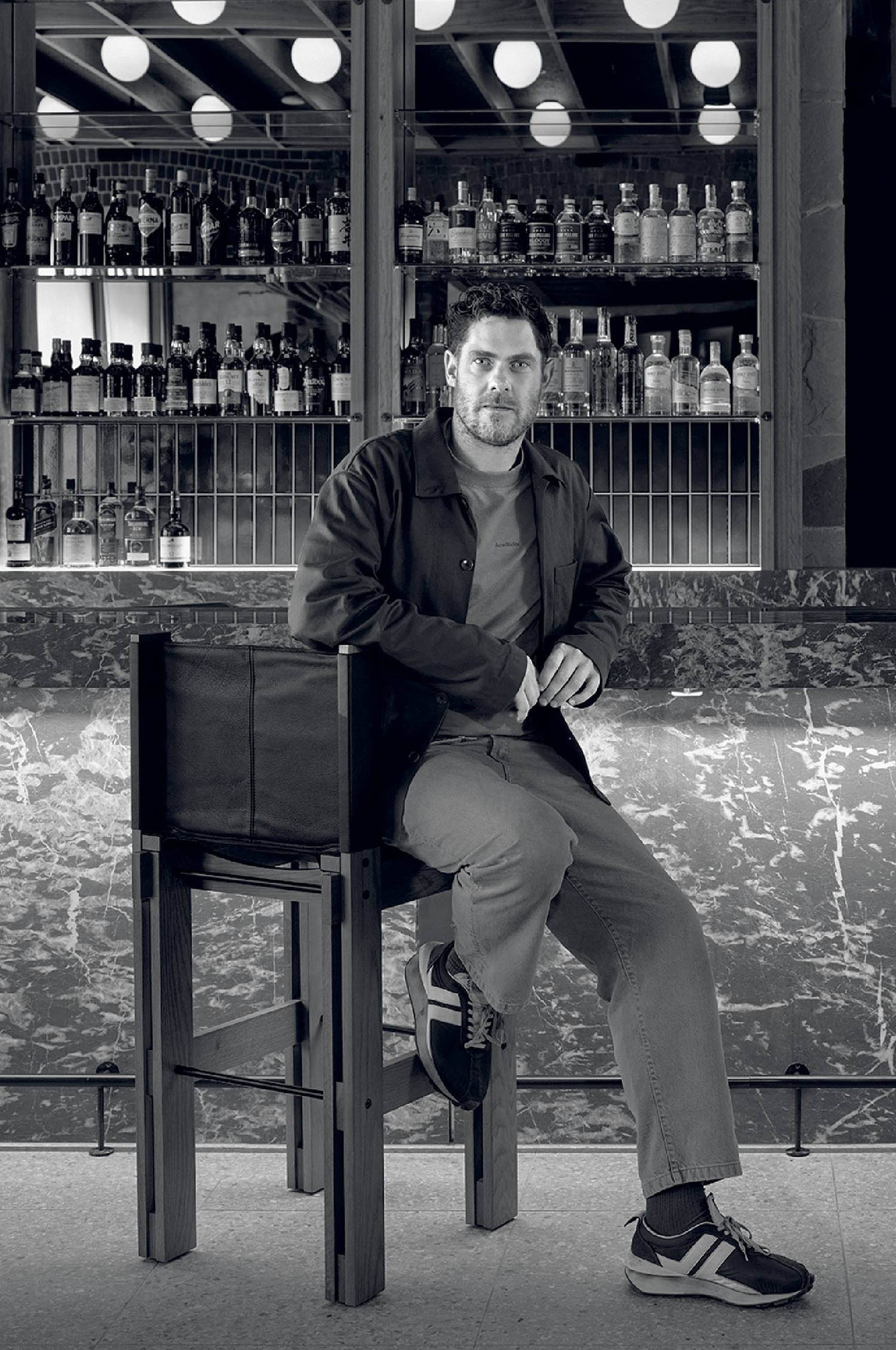 A man sitting on a chair in front of a bar.