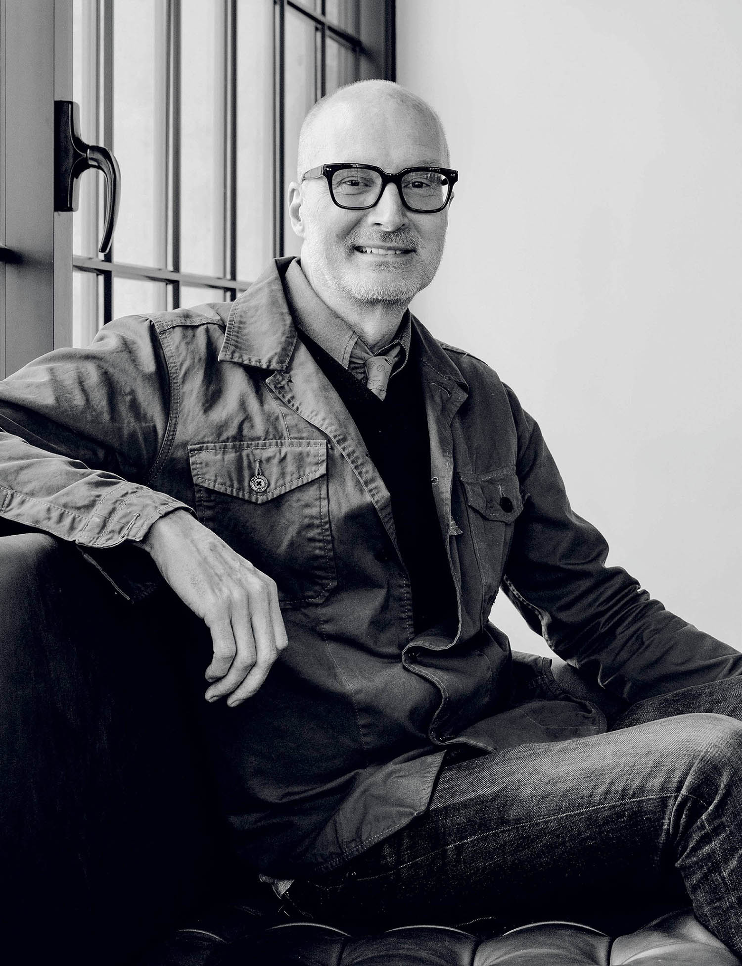 A man sitting on a couch with his hands on his knees.