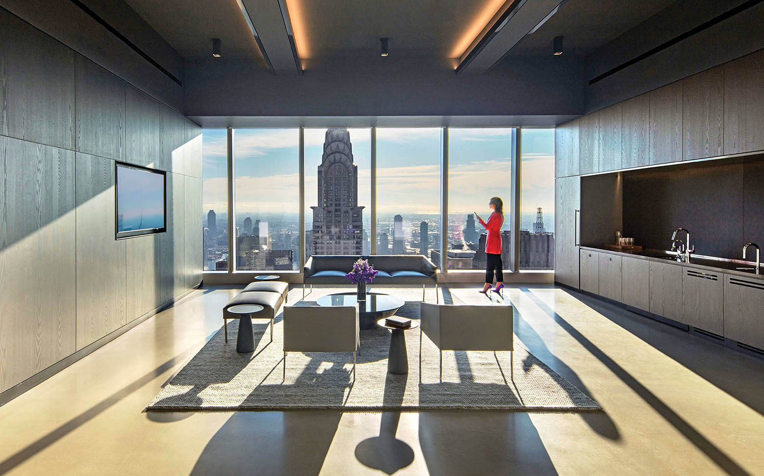 A woman standing in a living room with a view of the city.