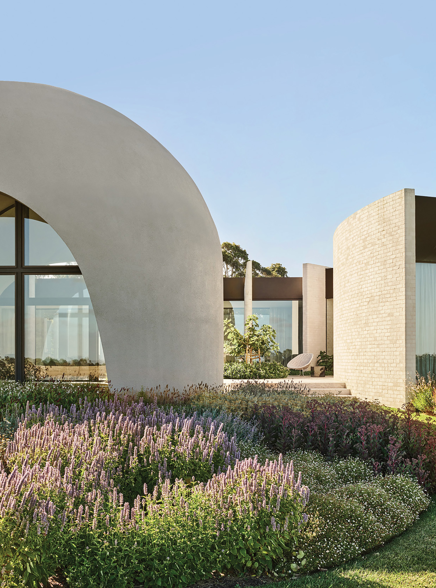 A garden with purple flowers and a white building