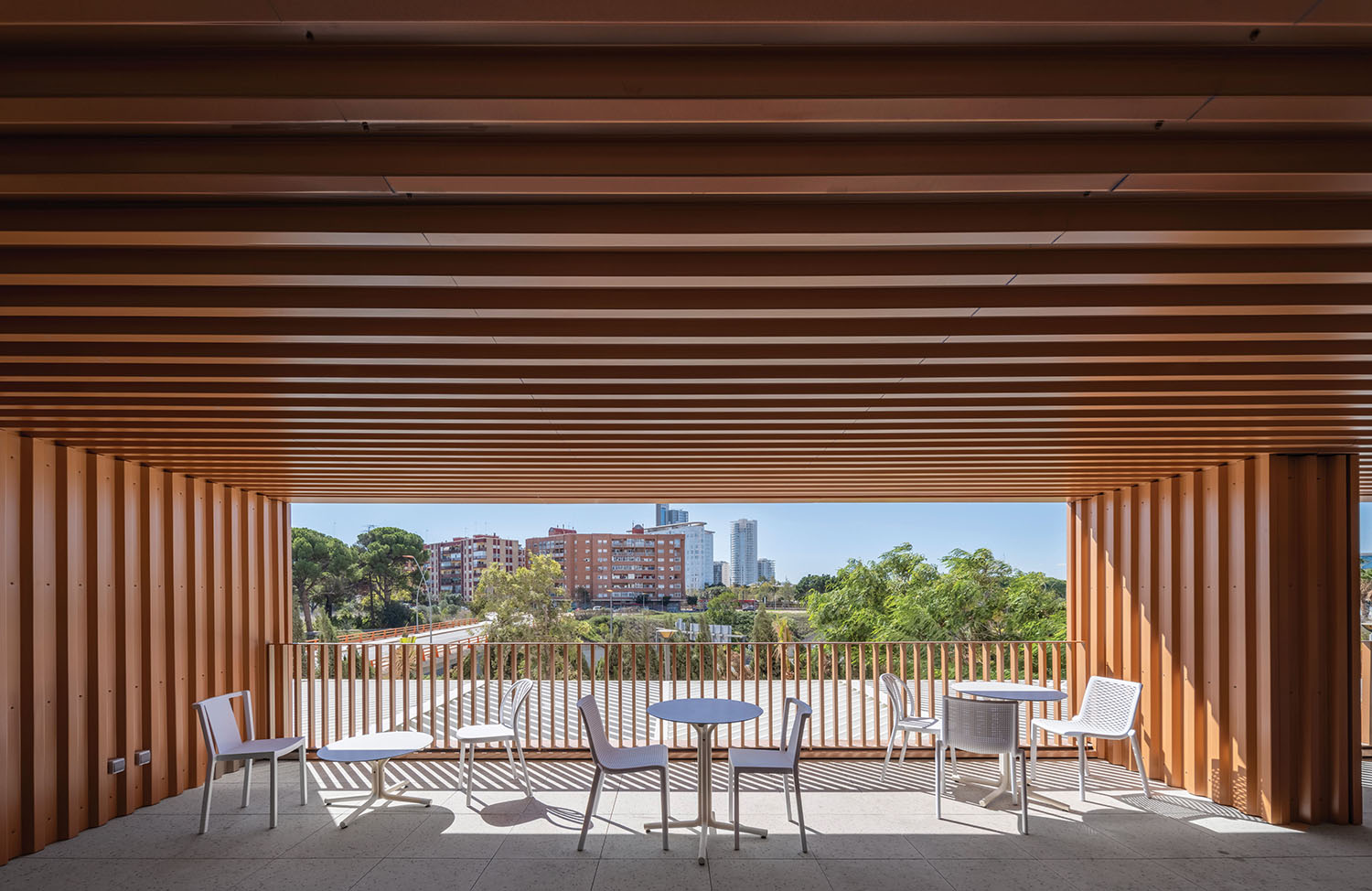 a wooden covered patio with white chairs and tables