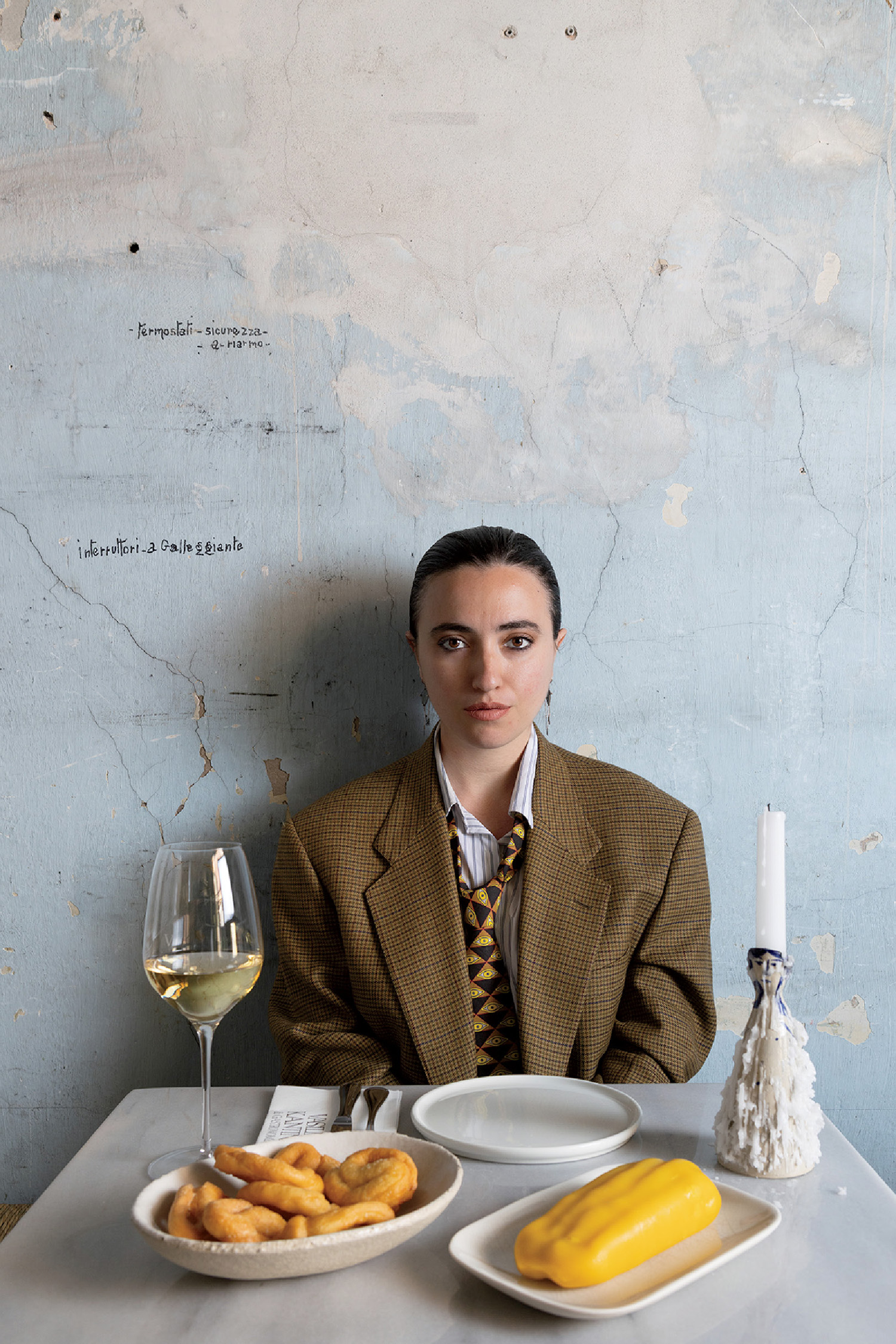 A woman sitting at a table with a plate of food and a glass of win