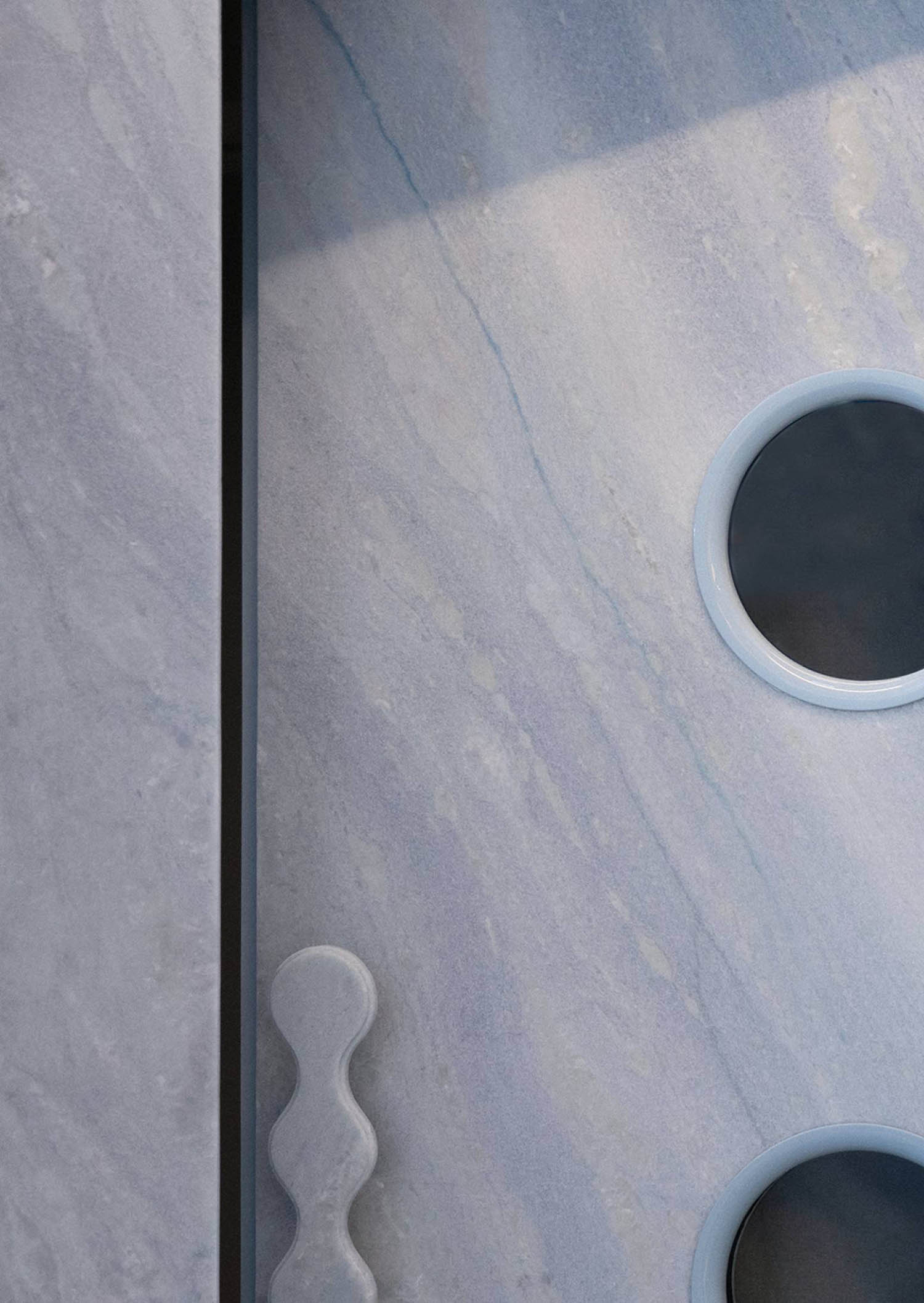A white marble shower with two round holes.