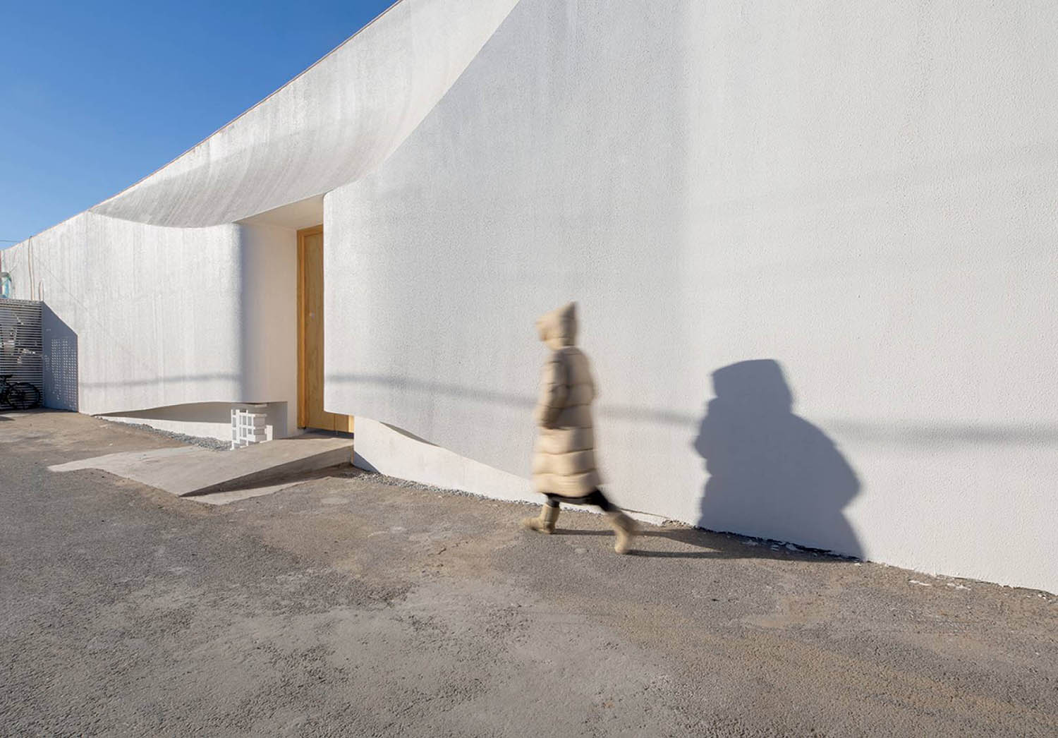 A person walking on a street next to a building.
