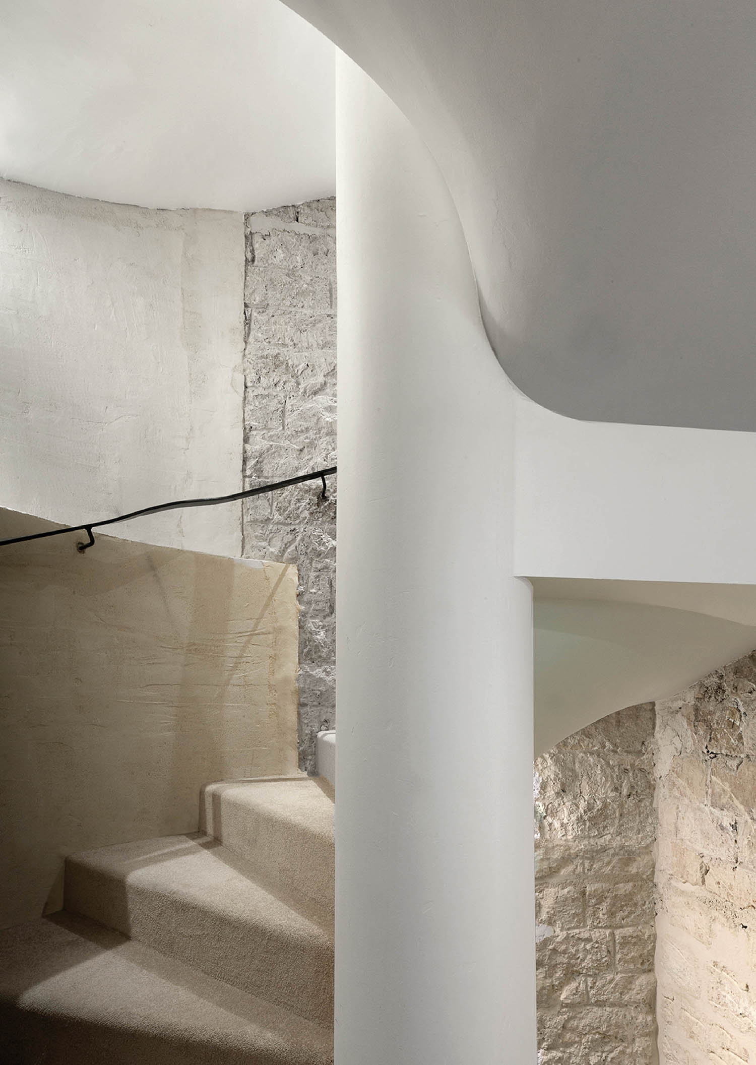 A staircase with a stone wall and a metal handrail.