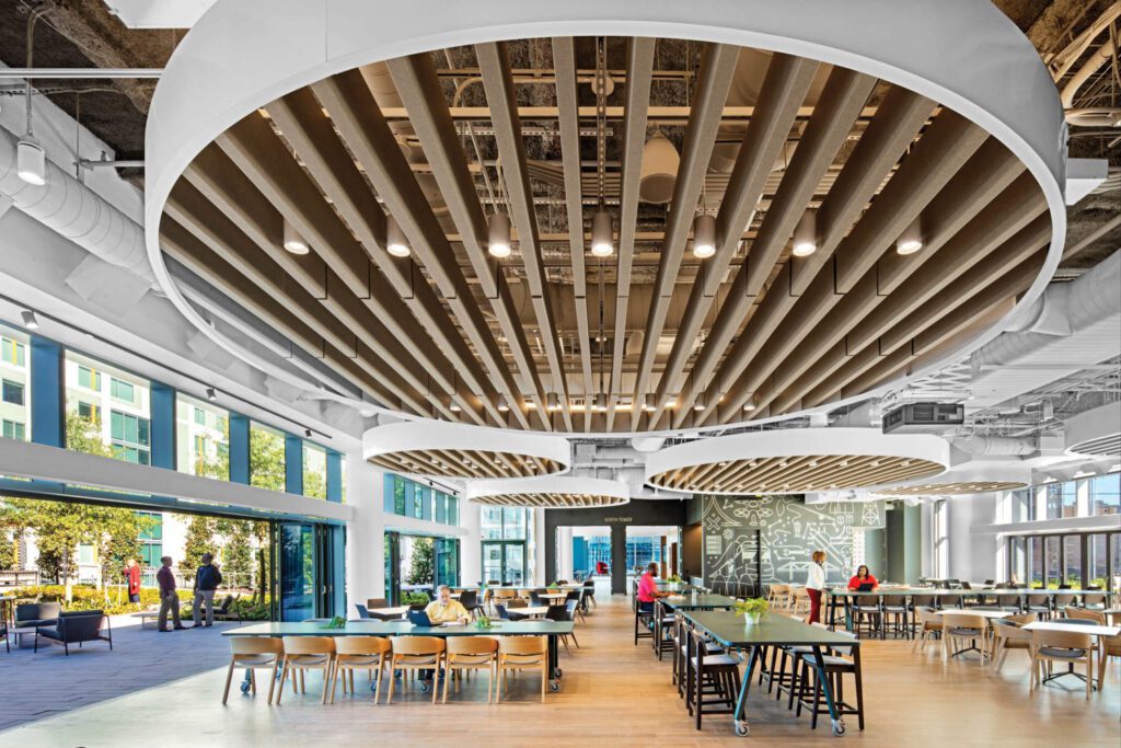 Beneath train track–inspired custom ceiling baffles, the employee canteen is fur­nished with Graham Design tables, Alexander Gufler armchairs, and black stools by Daniele Lo Scalzo Moscheri, and opens to a terrace on one side.
