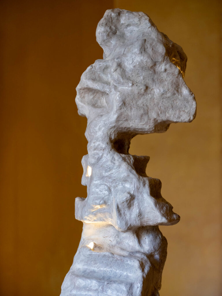 a gray sculptural column with lighting 