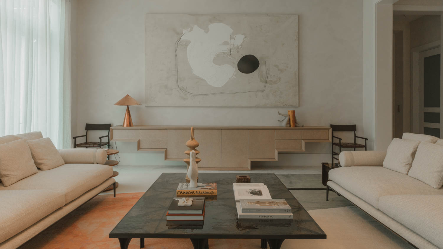 living room with white couches and black coffee table with books