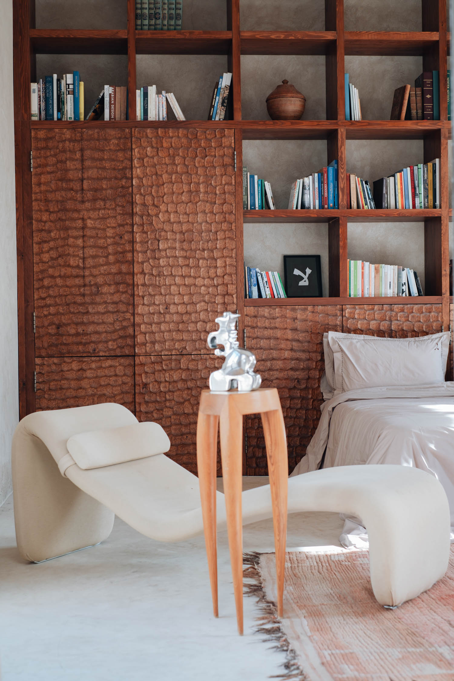 bedroom area with long white chairs and large bookshelf