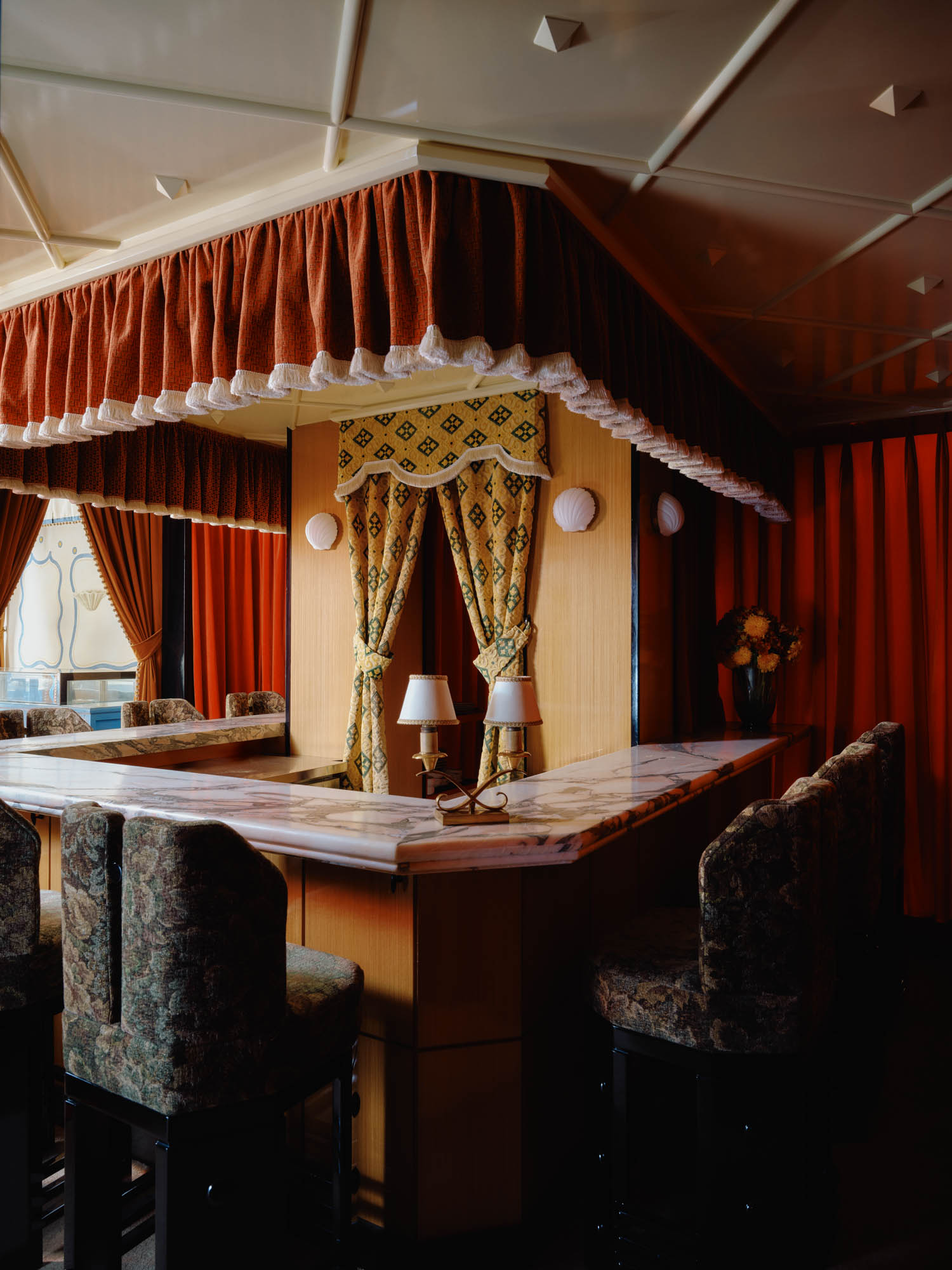 dessert bar area with red curtains on top and patterned chairs