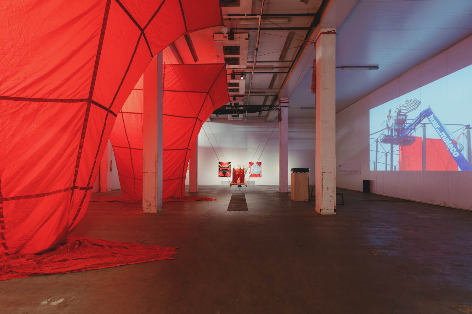 room with red draped sculptures and wooden beams